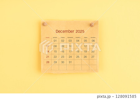 December 2025 brown calendar with wooden thumbtack on yellow color background. 128091585