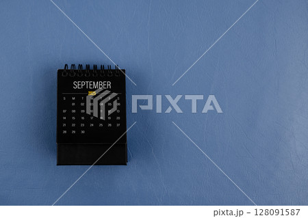 September 2025 black desk calendar on navy blue color leather background. September 2025 black desk calendar on navy blue color leather background. 128091587