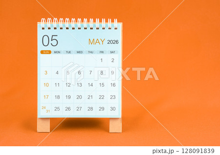May 2026 desk calendar stand on orange color textile background. 128091839