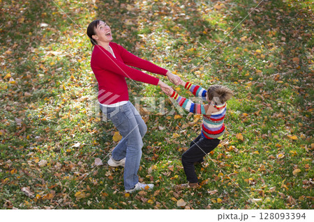 Mom and little son are walking in the autumn park. 128093394