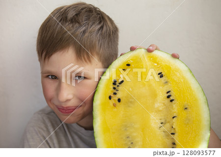 The boy is holding a large yellow watermelon.Child with fruit. The boy is holding a large yellow watermelon.Child with fruit. 128093577