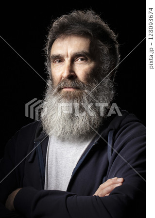 Portrait of an elderly man with a gray beard on a black background. 128093674