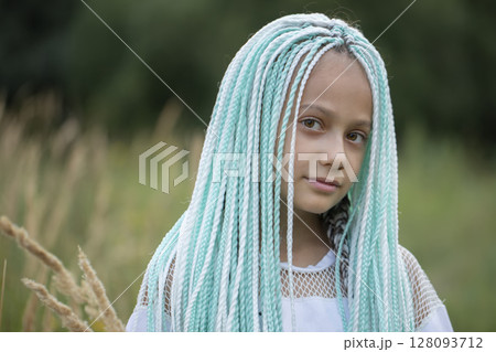 Fashionable little girl with multicolored African braids looks into the camera. Fashionable little girl with multicolored African braids looks into the camera. 128093712