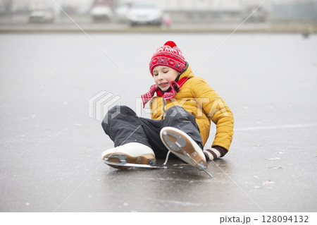 A little boy fell when he was learning to skate.A child on an ice rink. 128094132