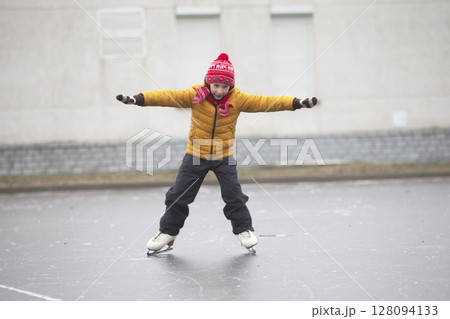 Little boy in winter clothes learns to skate.A child on an ice rink. 128094133