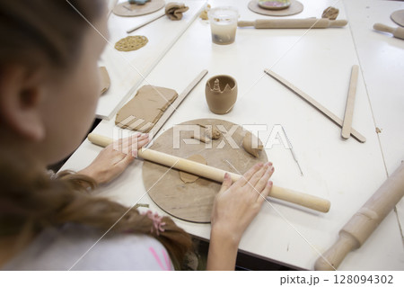 Master class in clay modeling. A teenage girl sculpts from clay. 128094302