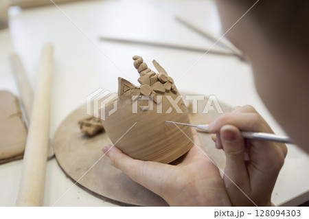 Clay modeling workshop. A girl sculpts a cup from clay. Clay modeling workshop. A girl sculpts a cup from clay. 128094303