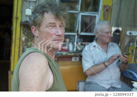 An adult son on the background of an elderly old man's father. Father and son. An adult son on the background of an elderly old man's father. Father and son. 128094337