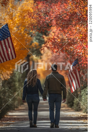 couple holding hands with usa flags behind their backs walking in park 128095994