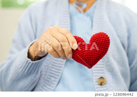 Asian elder senior woman patient holding red heart in hospital. Asian elder senior woman patient holding red heart in hospital. 128096442