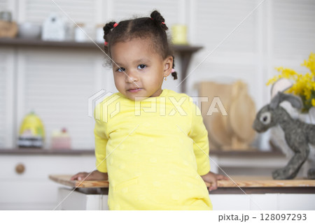 Portrait of a little African American girl on a kitchen background. Portrait of a little African American girl on a kitchen background. 128097293