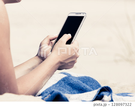 Woman on beach texting on smartphone. 128097322