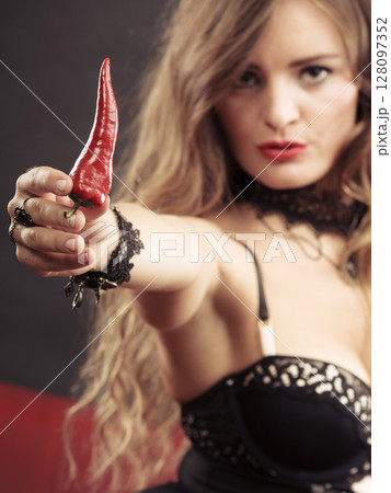 Woman wearing lingerie holding chilli pepper Woman wearing lingerie holding chilli pepper 128097352