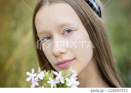 Portrait of a teenage girl with Korean makeup. Cute blonde girl holding wildflowers. Portrait of a teenage girl with Korean makeup. Cute blonde girl holding wildflowers. 128097833