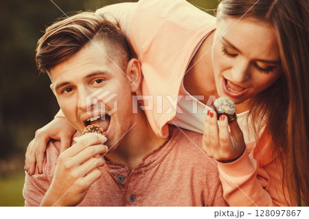 Lovely couple eating cupcakes. Lovely couple eating cupcakes. 128097867