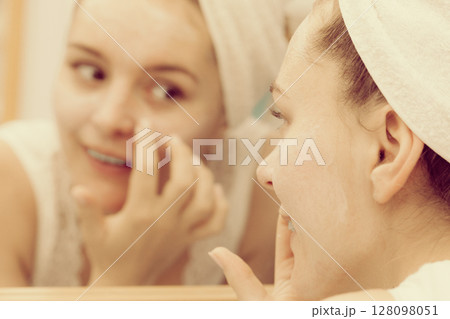 Woman applying mask cream on face in bathroom 128098051