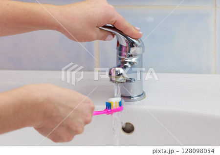 Hand holding toothbrush in bathroom Hand holding toothbrush in bathroom 128098054