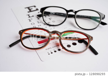 Glasses on eye exam chart to test eyesight accuracy of reading. 128098293