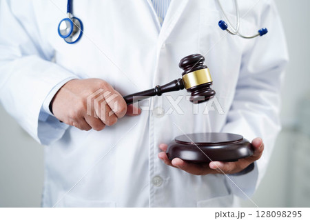 Asian doctor holding court hammer for and crime law justice, forensic medicine. 128098295