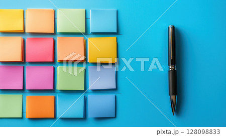 Colorful sticky notes arranged in neat rows on blue surface with black pen casting soft shadow, creating organized workspace feel 128098833