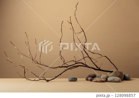 An intricately entwined branches and smooth stones against a beige background. 128098857