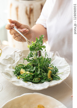 Woman eating green salad with avocado and arugula Woman eating green salad with avocado and arugula 128098931