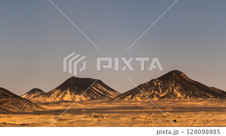 Ash-covered hills in Egypt's Black Desert under a clear sky, scenic and remote landscape. Volcanic	 128098985