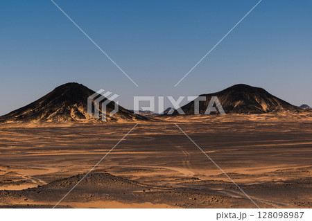 Ash-covered hills in Egypt's Black Desert under a clear sky, scenic and remote landscape. Volcanic	 128098987