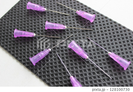Open needles for disposable syringes are scattered on a black medical napkin Open needles for disposable syringes are scattered on a black medical napkin 128100730