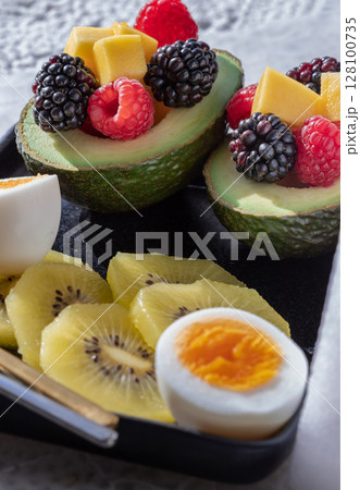 A colorful healthy food with redberry, blackberry and mango on avocado with golden kiwi and boiled egg on vibrant eating ceramic dish. A colorful healthy food with redberry, blackberry and mango on avocado with golden kiwi and boiled egg on vibrant eating ceramic dish. 128100735