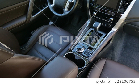 Top view of the center panel and armrest between the seats in leather trim inside a modern car Top view of the center panel and armrest between the seats in leather trim inside a modern car 128100753