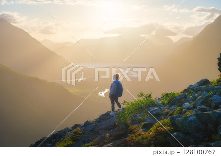 A young athletic girl standing on a rock with a backpack. Norway. A young athletic girl standing on a rock with a backpack. Norway. 128100767