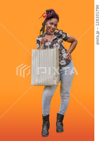Black Woman Shopping with Striped Bag Orange Background Black Woman Shopping with Striped Bag Orange Background 128101790
