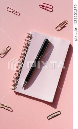 A black pen on a pink notebook with paperclips, ideal for writing or note-taking. A black pen on a pink notebook with paperclips, ideal for writing or note-taking. 128101879