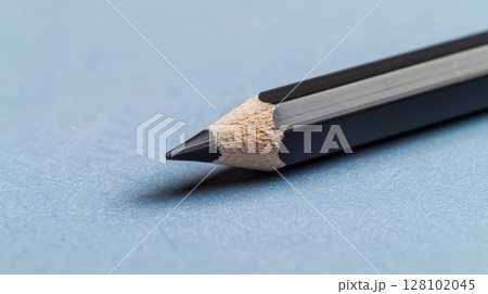 Black pencil on blue paper. Simple setup for drawing or school themes, perfect for art or education designs. Ideal for creative or minimalist visuals. 128102045