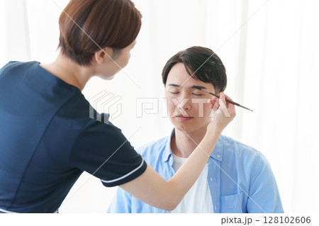 美容部員に眉毛のメイクをしてもらう男性 128102606