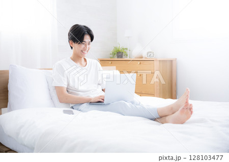 ベッドでパソコンをする男性　フリーランスや忙しい会社員のイメージ　広角 128103477