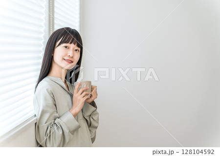 窓辺でホットドリンク,お茶,コーヒーを飲む若いアジア人女性 128104592