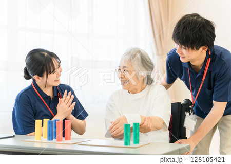 介護施設・リハビリ施設で働く作業療法士の職員とリハビリをするシニア女性 128105421