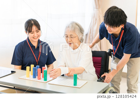 介護施設・リハビリ施設で働く作業療法士の職員とリハビリをするシニア女性 128105424