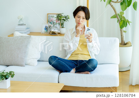 部屋でスマホを使うミドル女性 128106784