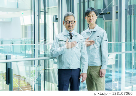 オフィスビルの中に立つ胸に手を当てる2人の作業員 撮影協力:スカパー東京メディアセンター オフィスビルの中に立つ胸に手を当てる2人の作業員 撮影協力:スカパー東京メディアセンター 128107060
