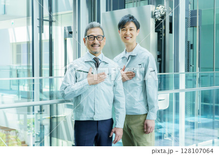 オフィスビルの中に立つ胸に手を当てる2人の作業員 撮影協力:スカパー東京メディアセンター オフィスビルの中に立つ胸に手を当てる2人の作業員 撮影協力:スカパー東京メディアセンター 128107064
