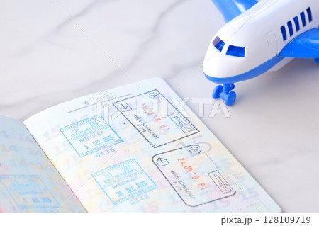 日本のパスポートを開いたビザのページと、飛行機で、長期休暇に海外旅行を計画しているイメージ 日本のパスポートを開いたビザのページと、飛行機で、長期休暇に海外旅行を計画しているイメージ 128109719