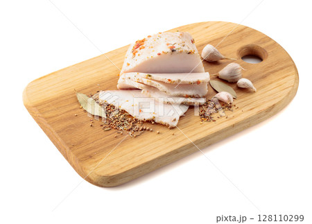 Salted lard with spices on a cutting board. 128110299