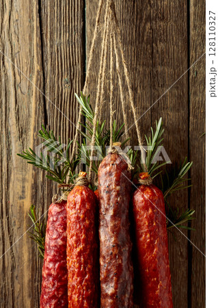 Smoked and dry cured sausages on a old wooden background. Smoked and dry cured sausages on a old wooden background. 128110327