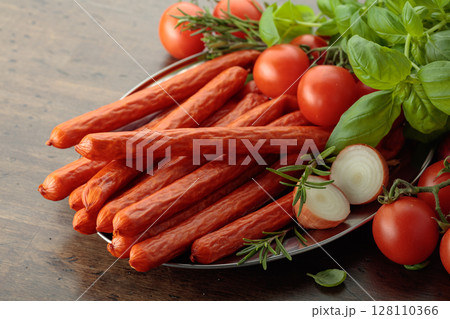 Kabanos sausages with basil and tomatoes on a old table. 128110366