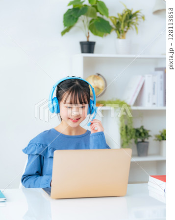 ヘッドホンをつけてノートパソコンで勉強する女の子 128113858
