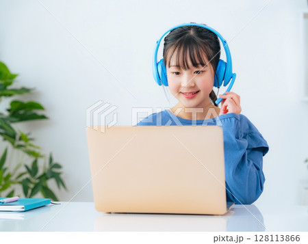 ヘッドホンをつけてノートパソコンで勉強する女の子 ヘッドホンをつけてノートパソコンで勉強する女の子 128113866