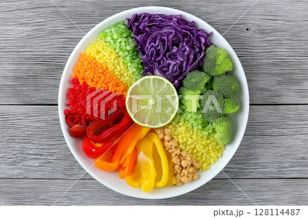 The concept of healthy vegetarian food is represented by a vegan detox Buddha bowl containing avocado, tomato, red cabbage, chickpea, fresh lettuce salad, pumpkin, and persimmon 128114487